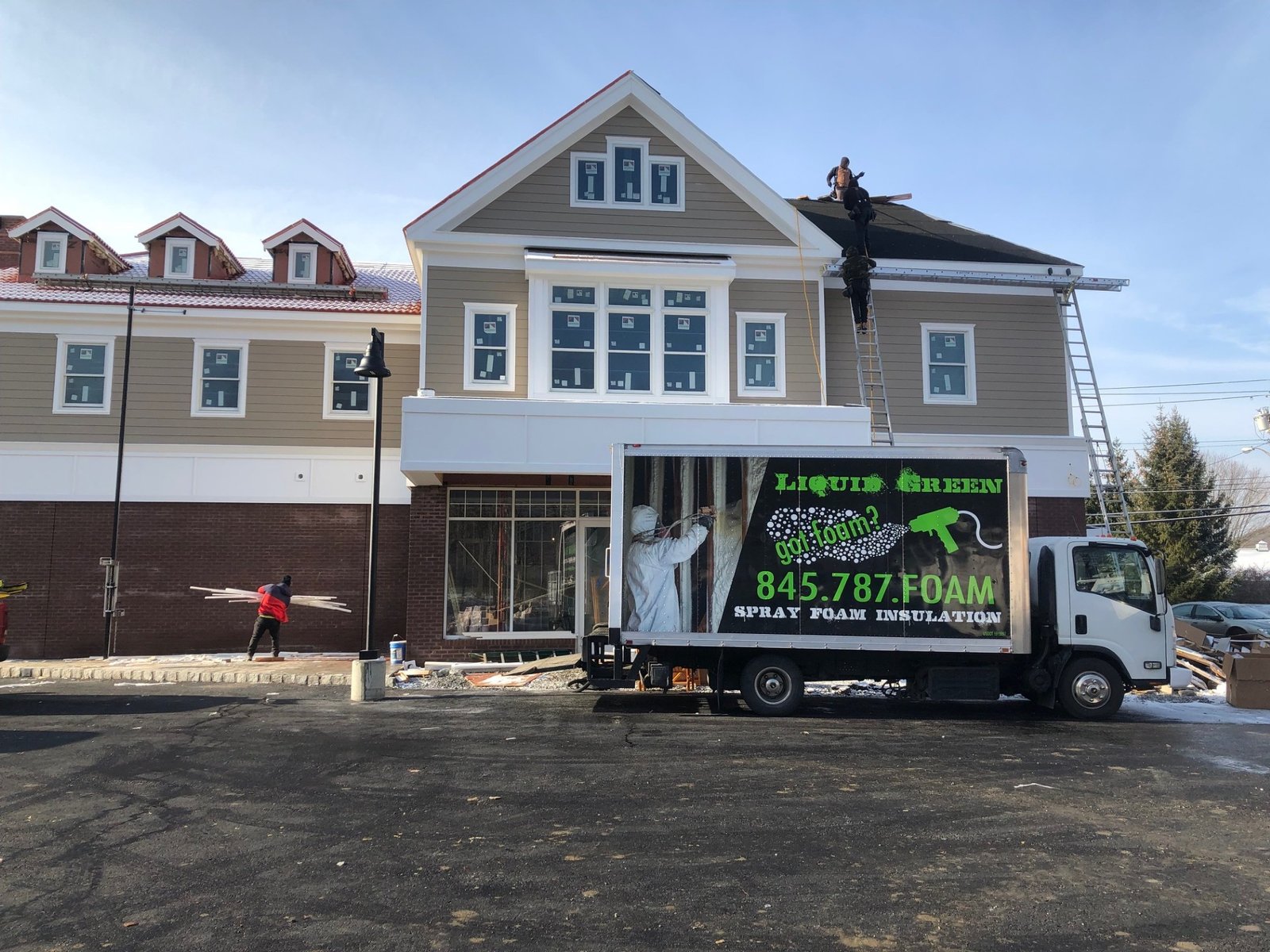 Liquid Green truck at residential job site with crew working on the roof